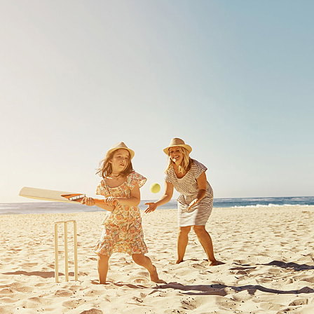 Girl playing cricket beach mum